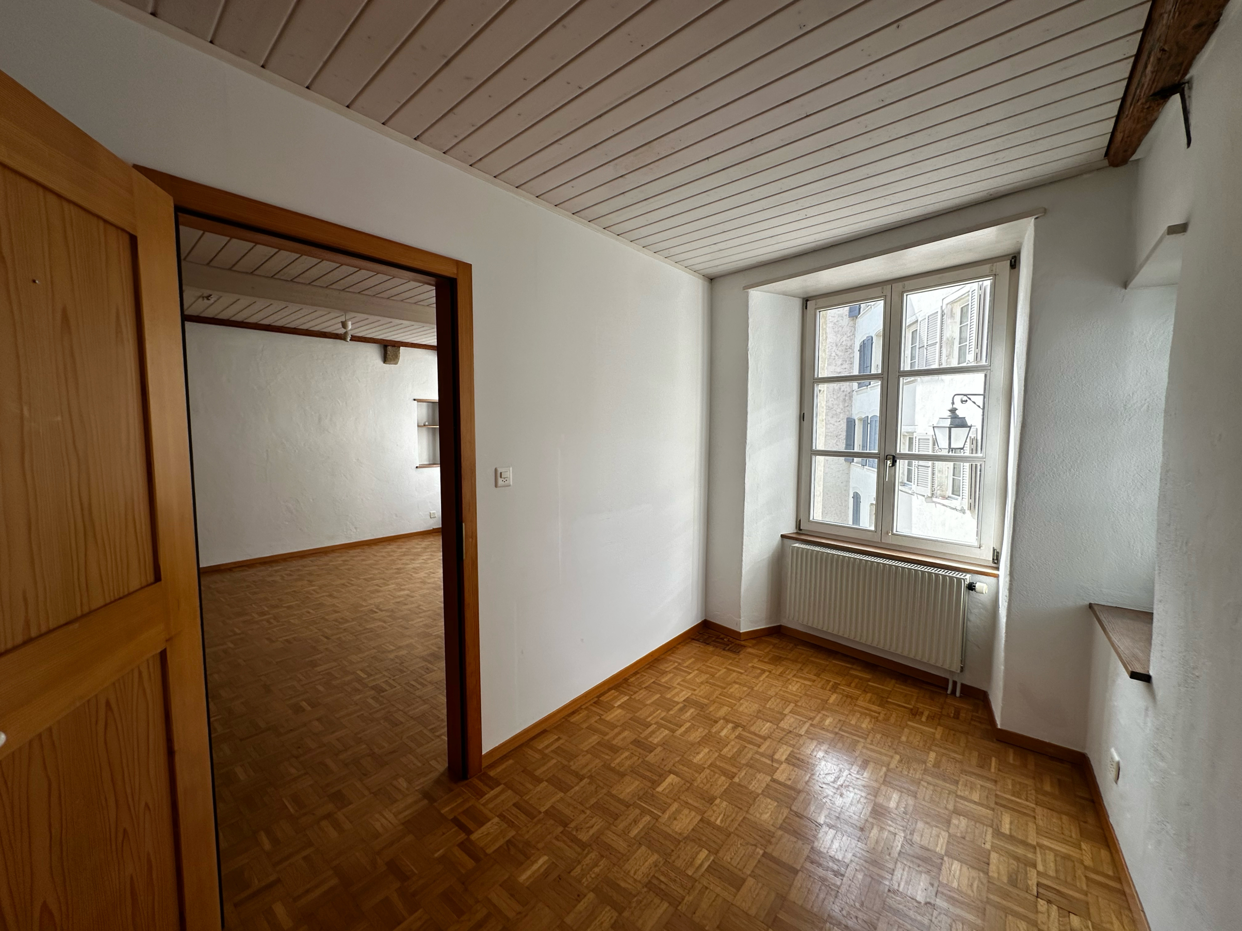 Heller Raum mit Parkett, Holzdecke und Fensterblick