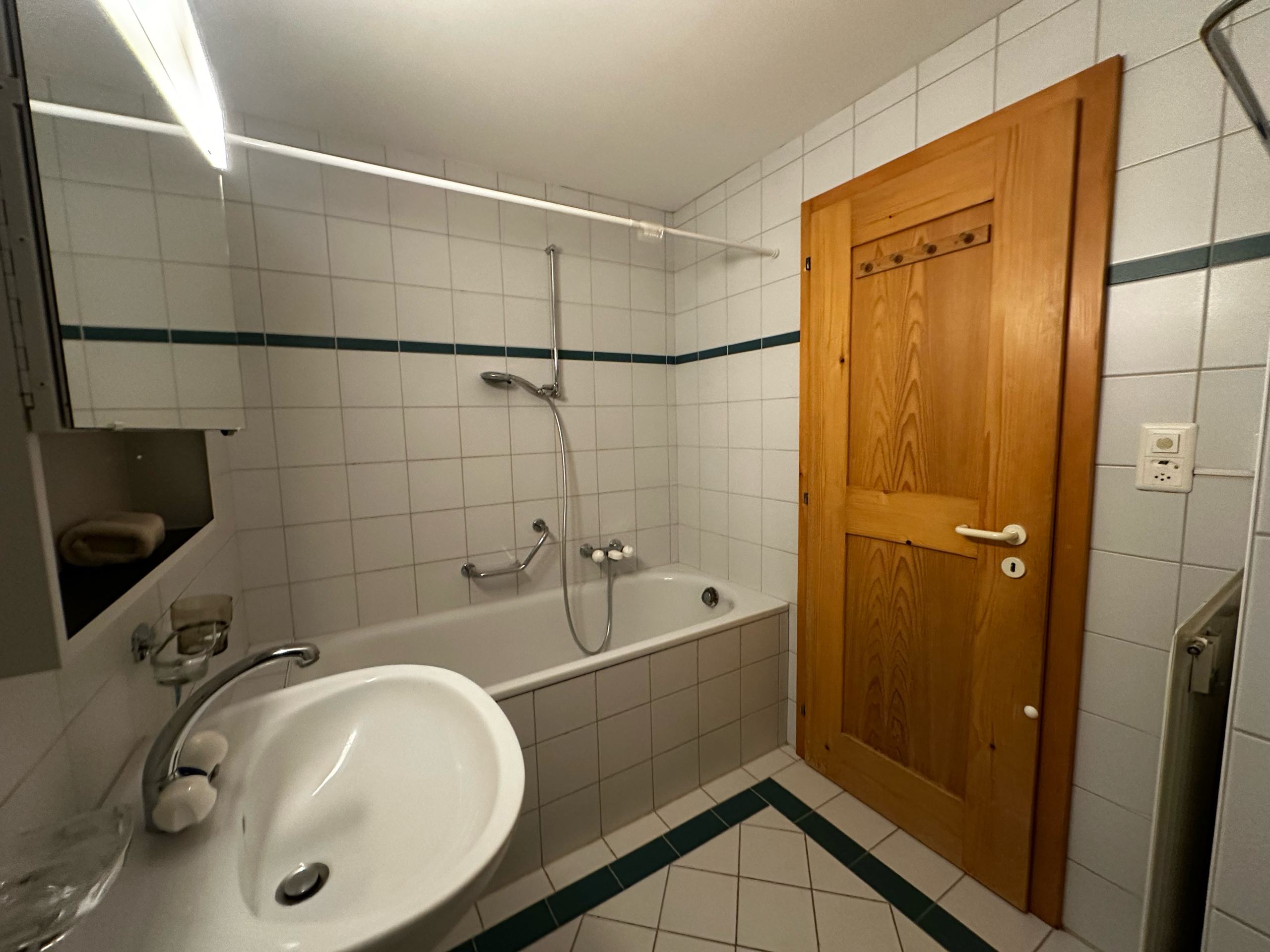 Badezimmer mit Badewanne und Holzinnentür