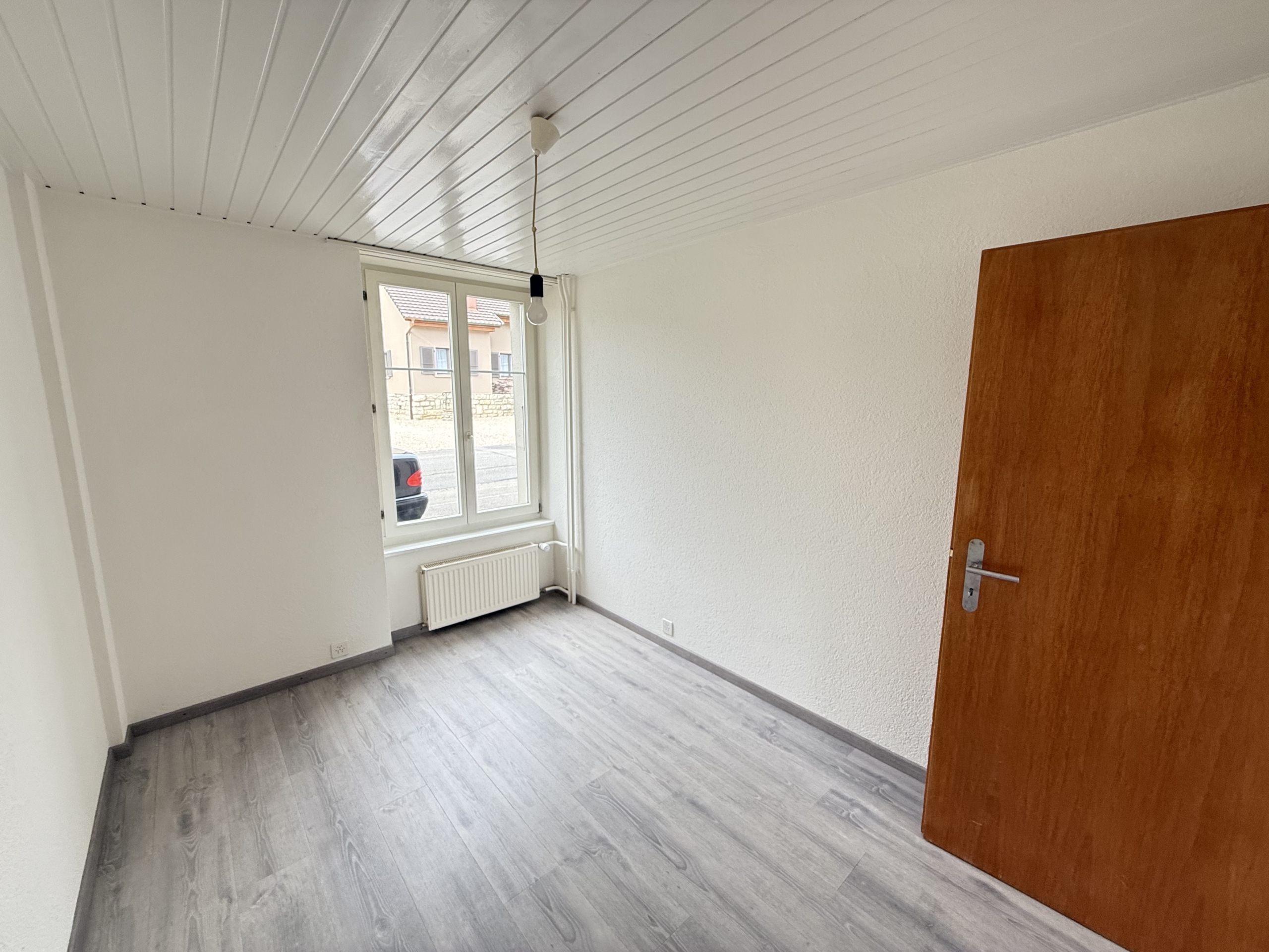 Heller leerer Raum mit Fenster und Holztür