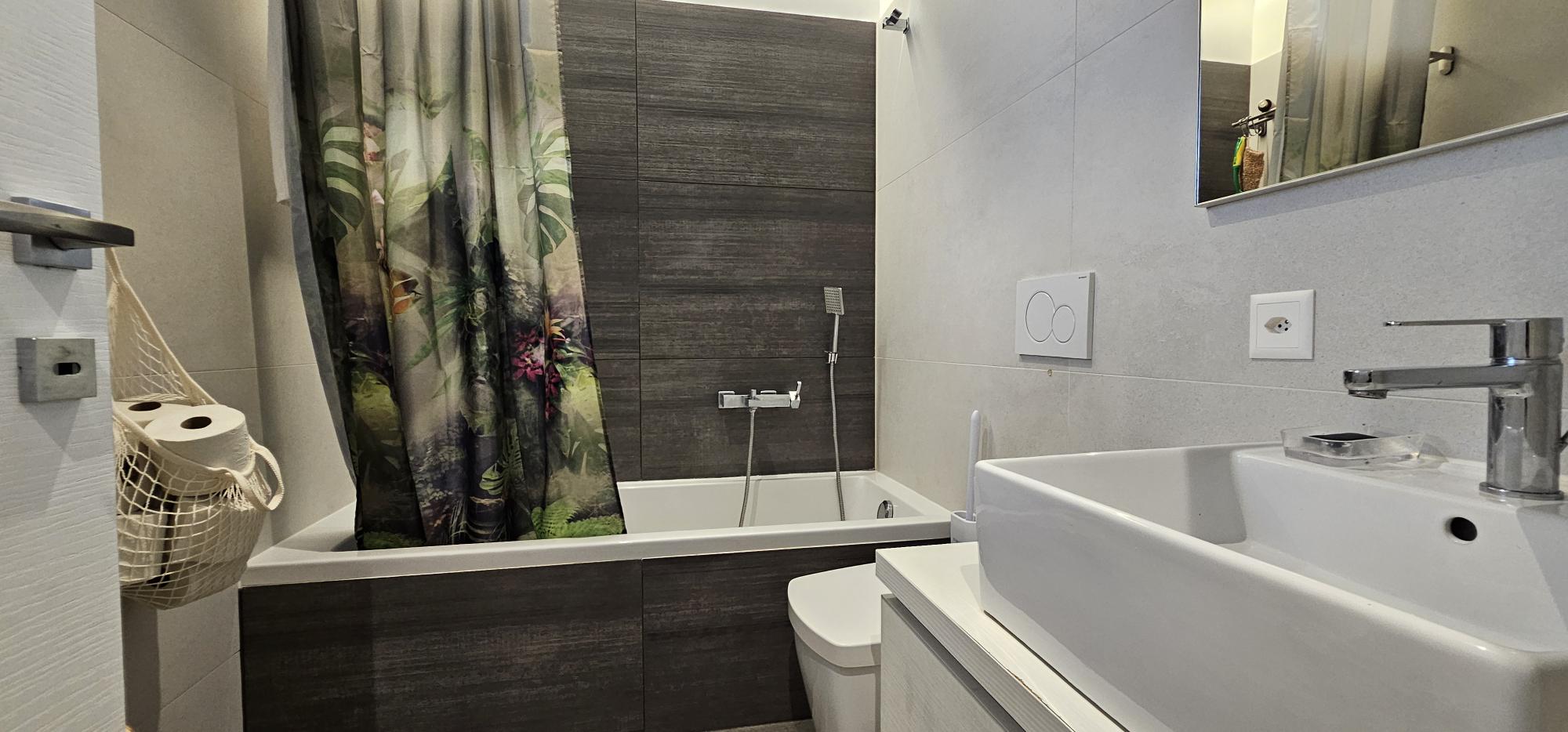 Modernes Badezimmer mit Wanne und Dschungelvorhang