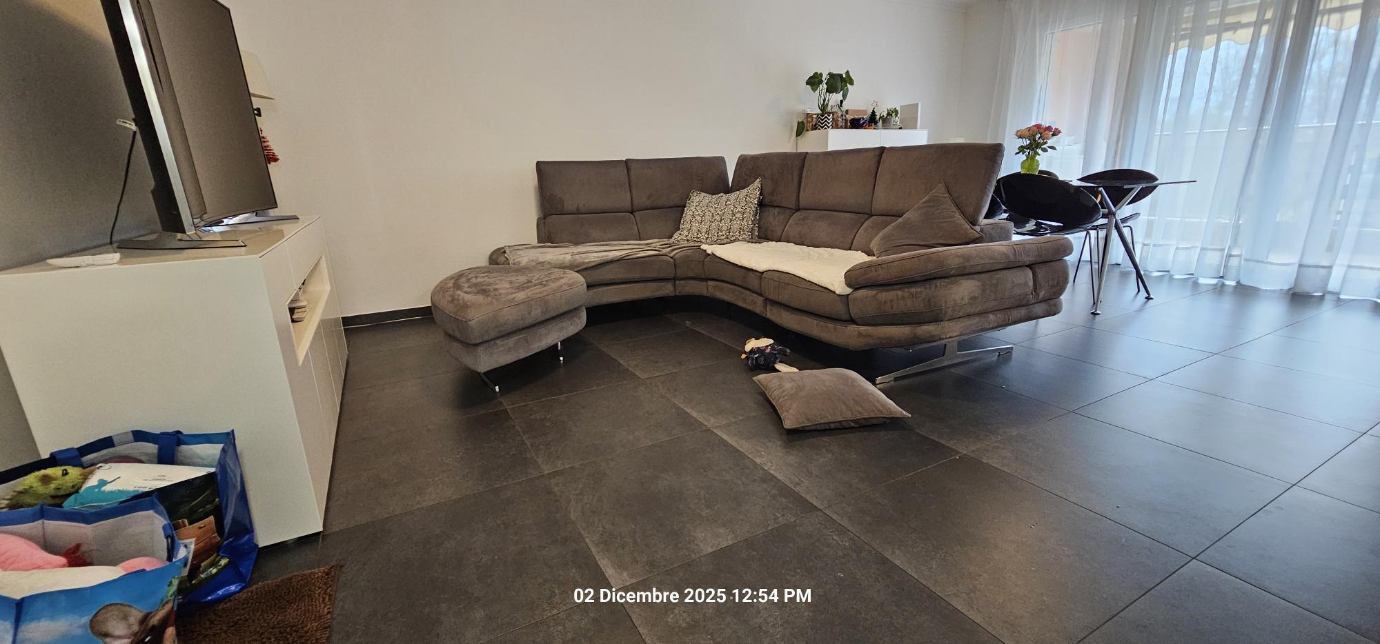 Wohnzimmer mit Ecksofa und Fliesenboden