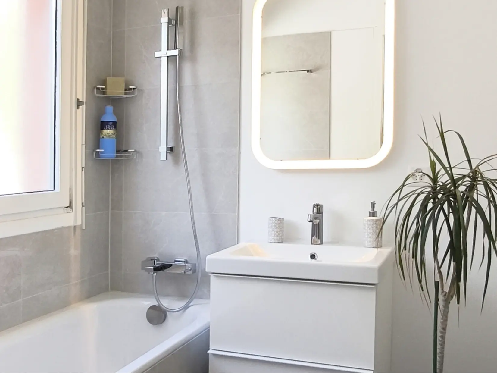 Modernes Badezimmer mit Badewanne und beleuchtetem Spiegel