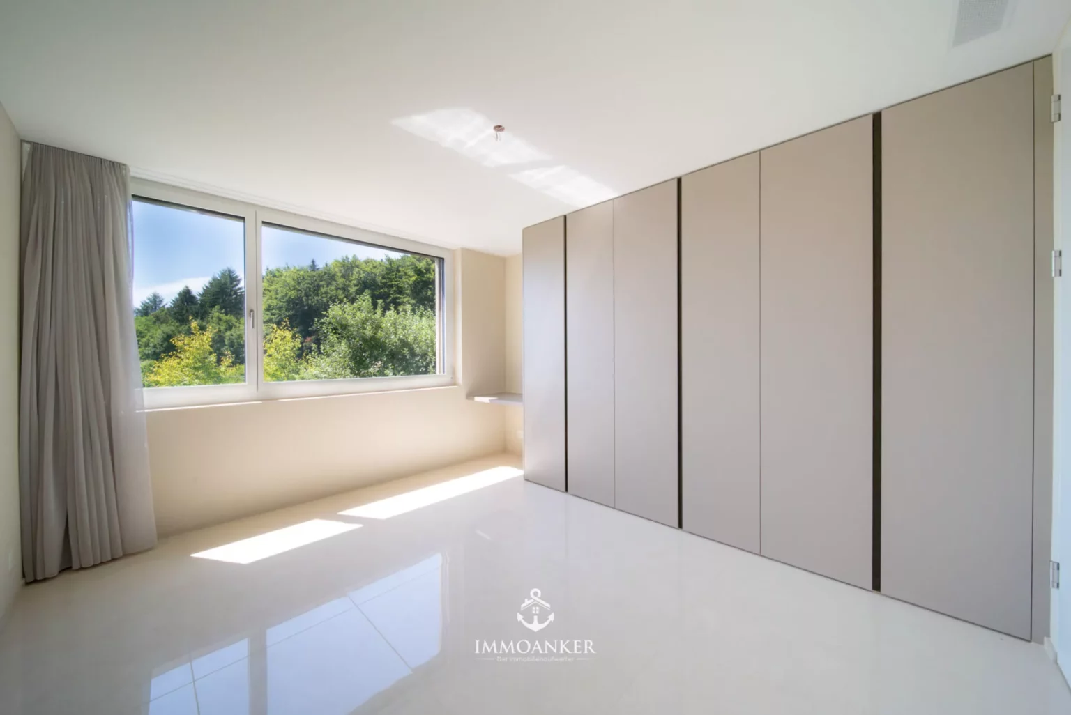 Helles Schlafzimmer mit Einbauschrank und Fensterblick ins Grüne