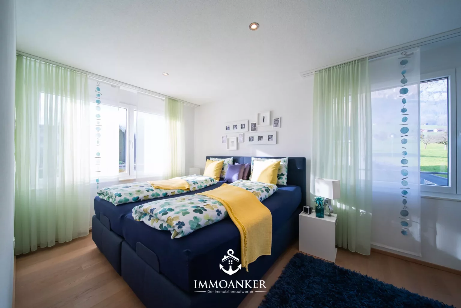 Helles Schlafzimmer mit Doppelbett und großen Fenstern