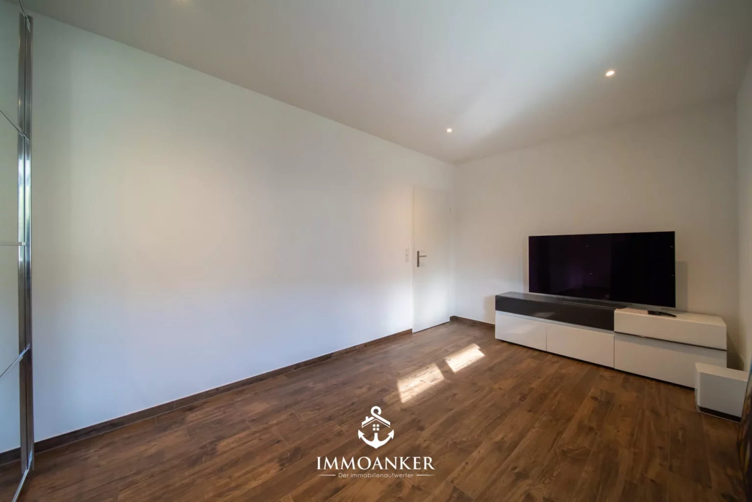 Helles, modernes Zimmer mit TV und Holzoptik-Boden