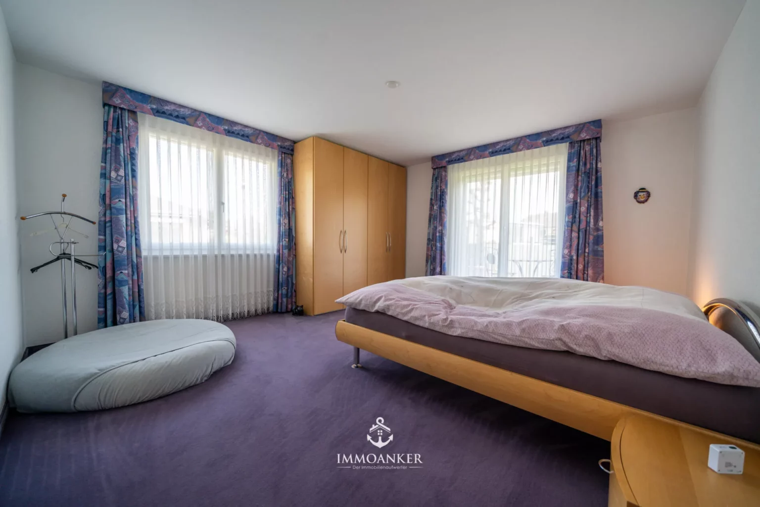 Schlafzimmer mit Kleiderschrank und großen Fenstern