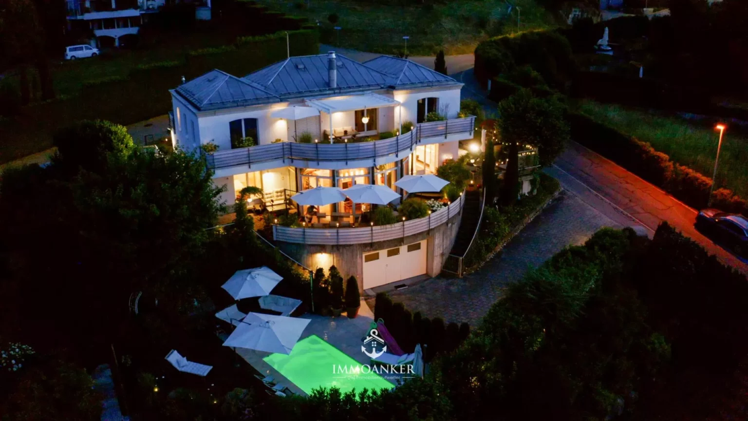 Nächtliche Außenaufnahme einer luxuriösen Villa mit Pool und Terrassen