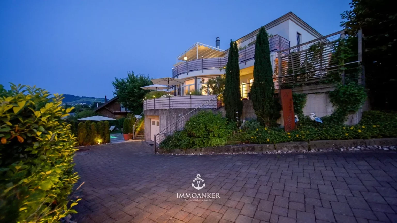 Moderne Villa mit Terrassen und Garten bei Dämmerung