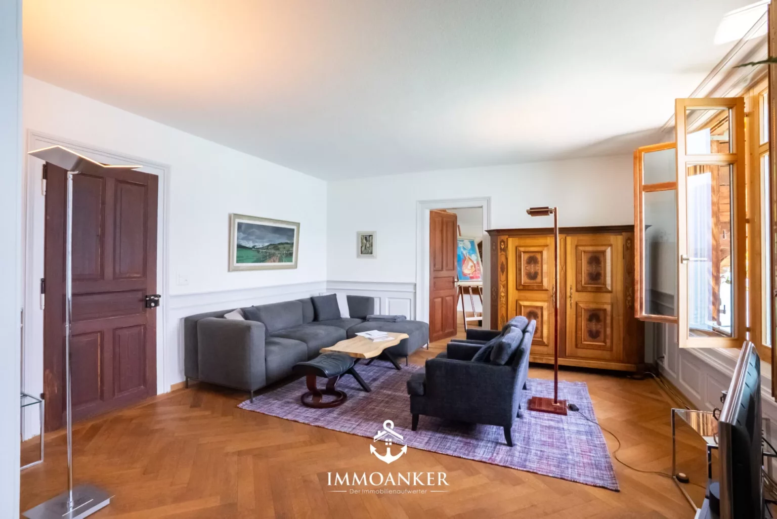Wohnzimmer mit Parkett, Sofa und Holzschrank