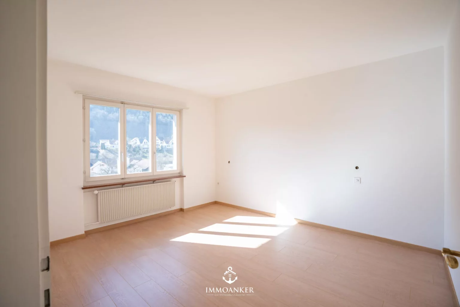 Leerer heller Wohnraum mit Fenster und Heizkörper