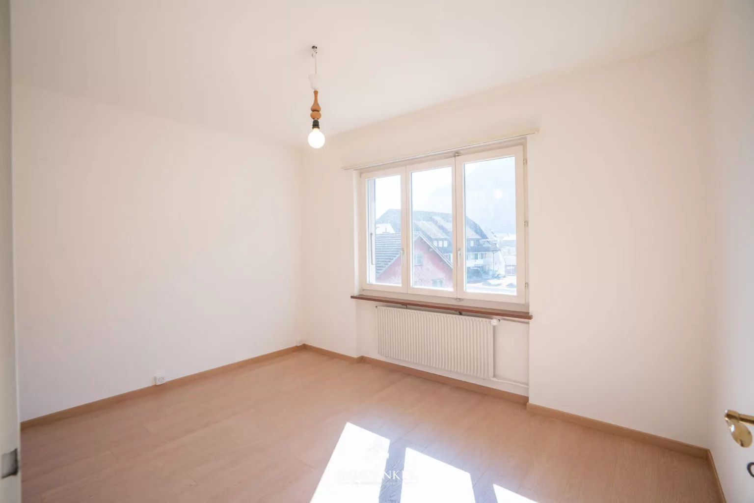 Helles, leeres Zimmer mit Fenster und Heizkörper