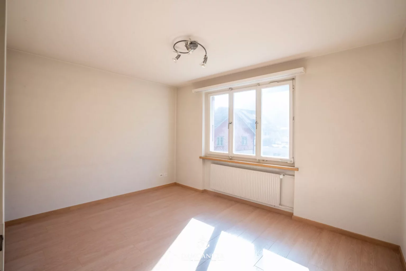 Leerer, heller Wohnraum mit Fenster und Heizkörper