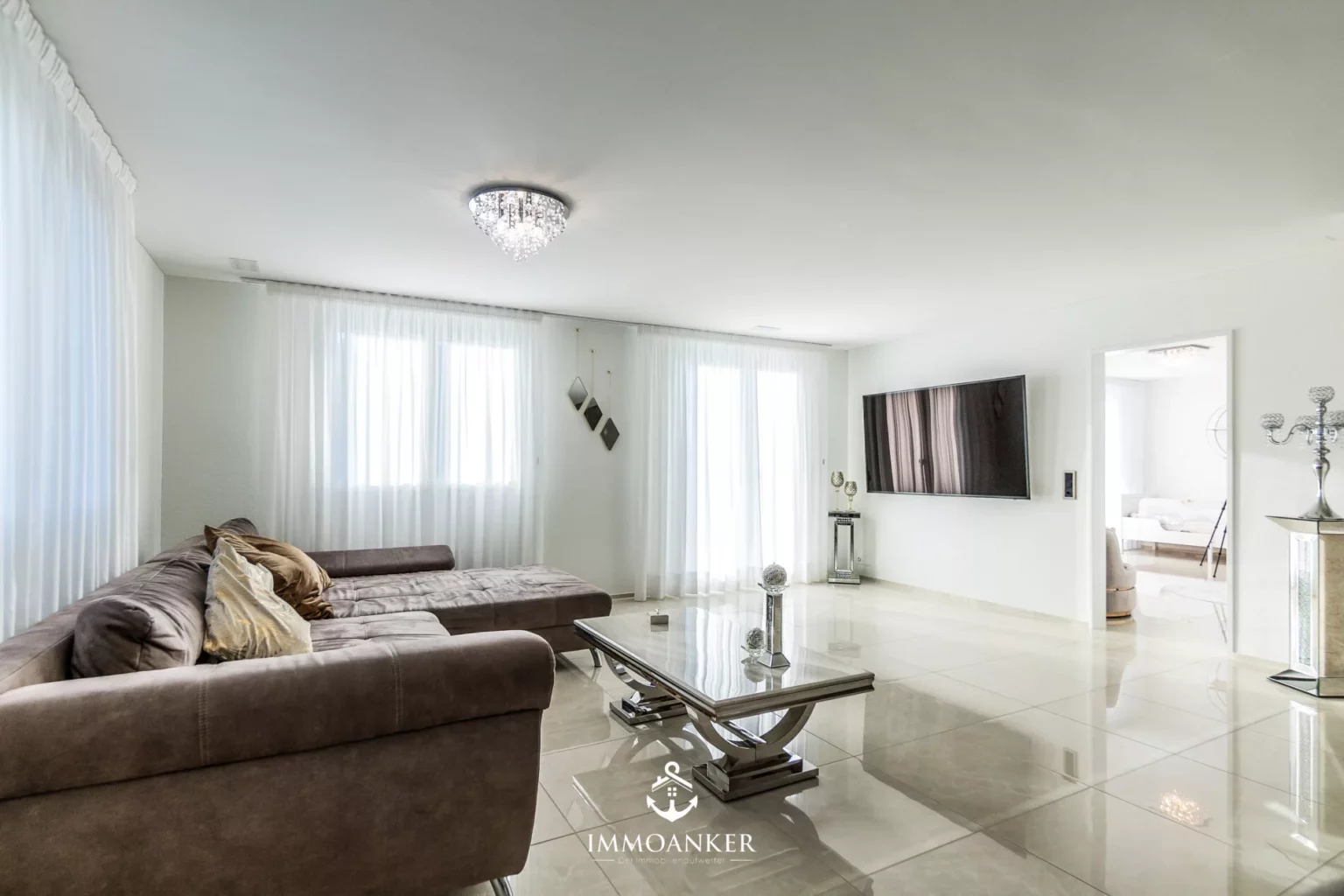 Heller, moderner Wohnraum mit Ecksofa und TV