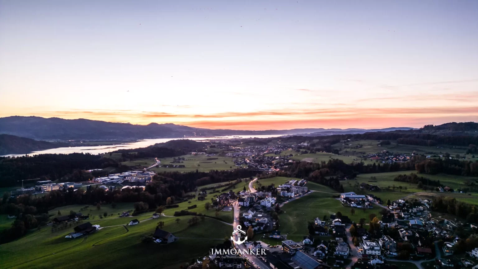 Luftaufnahme bei Sonnenuntergang über Landschaft und Siedlung