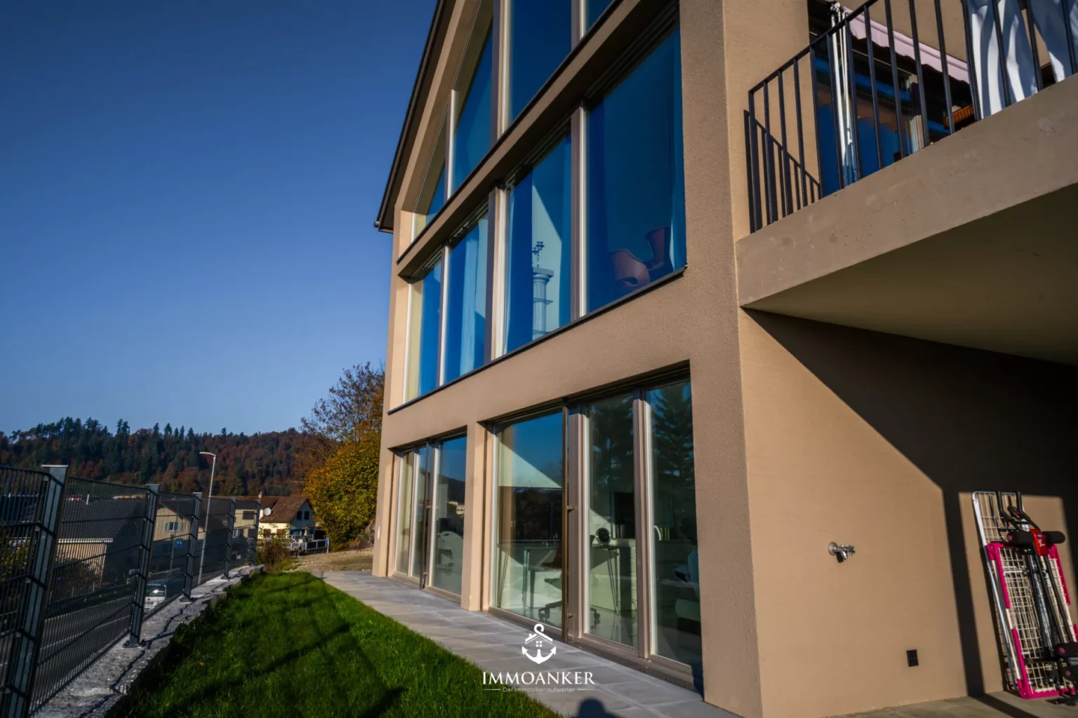 Moderne Außenansicht mit Balkon und großen Fensterflächen