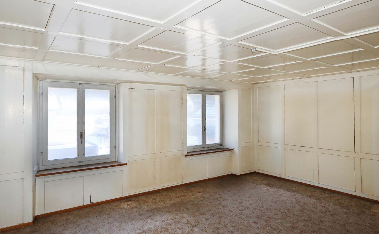Heller, leerer Raum mit Fenstern und Paneelwänden