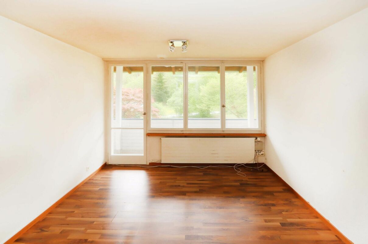Leerer, heller Wohnraum mit Balkonzugang