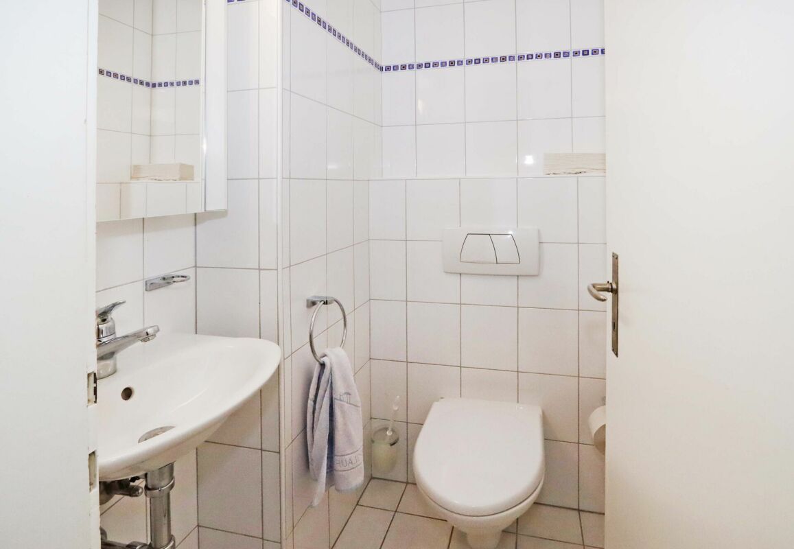 Kleines Gäste-WC mit weißer Fliesenverkleidung