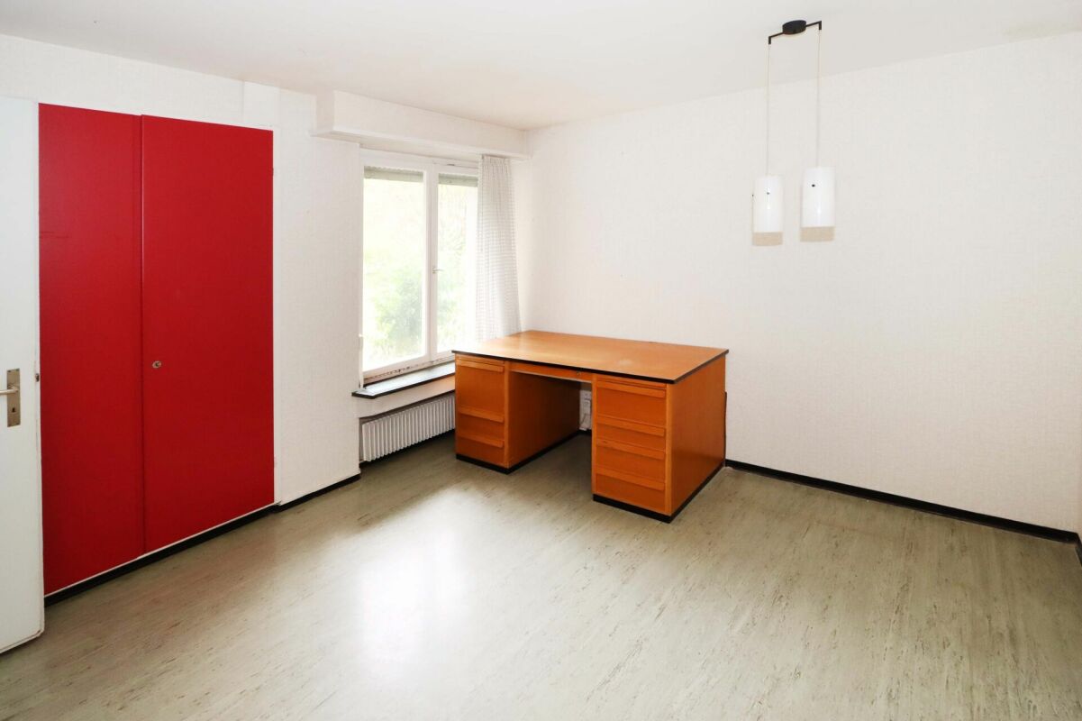 Ein schlichtes Arbeitszimmer mit auffälligem rotem Einbauschrank.