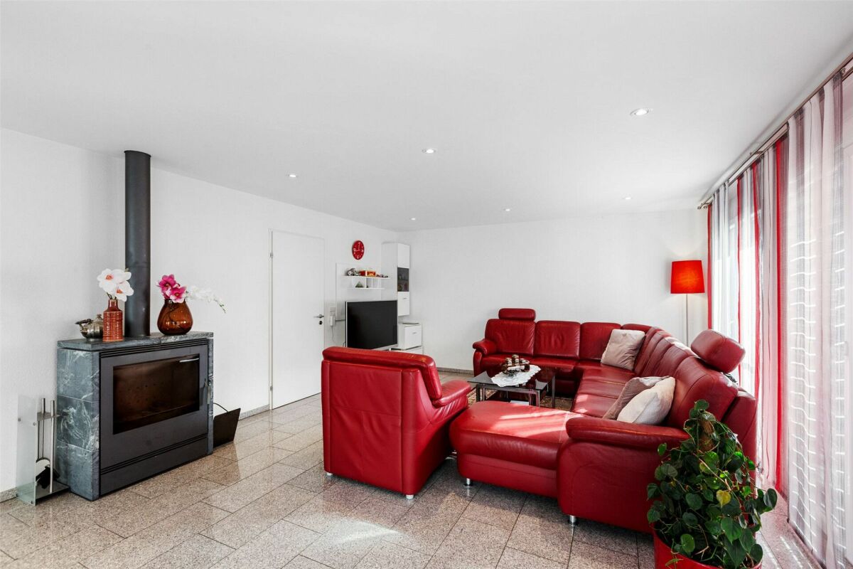 Wohnzimmer mit Kamin und rotem Ledersofa