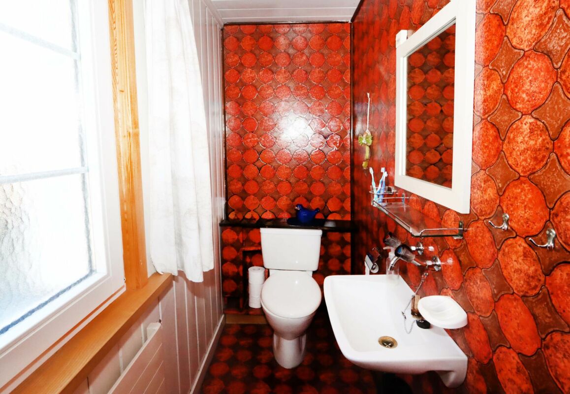 Kleines Badezimmer mit auffälliger rot-orangefarbener Wandgestaltung