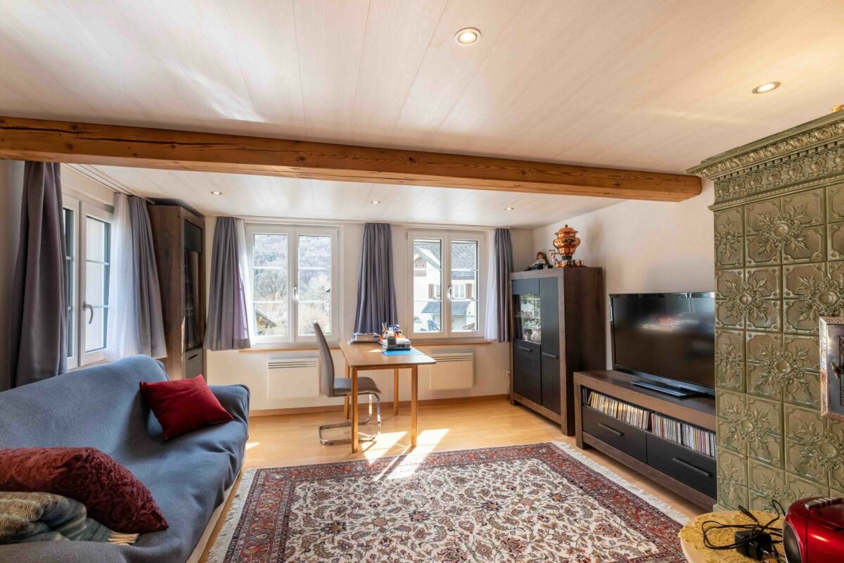 Gemütliches Wohnzimmer mit Holzbalken und Kachelofen