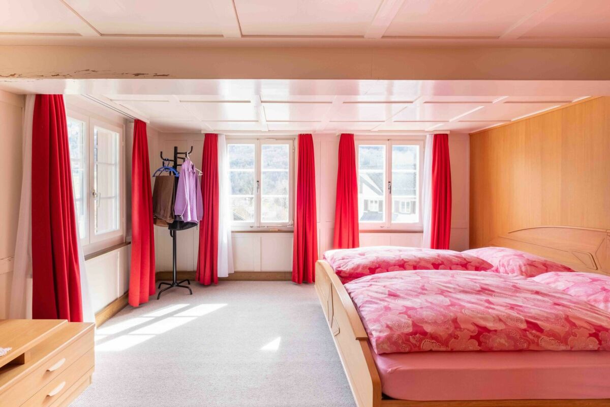 Helles Schlafzimmer mit roten Vorhängen und Doppelbett