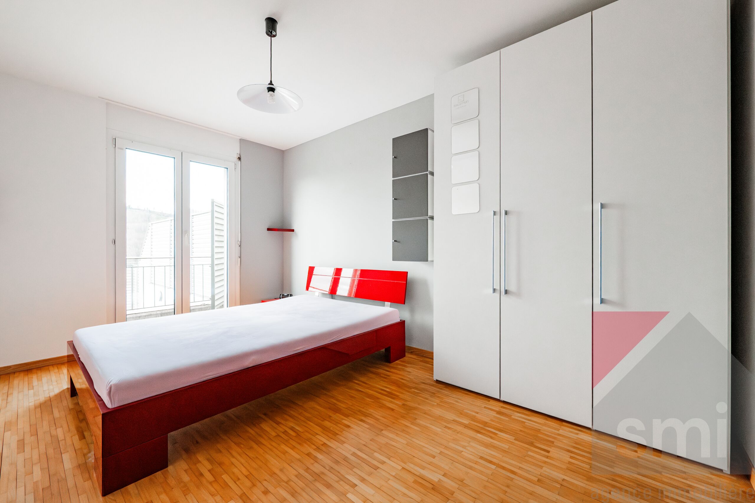 Schlafzimmer mit rotem Bett und weißem Schrank