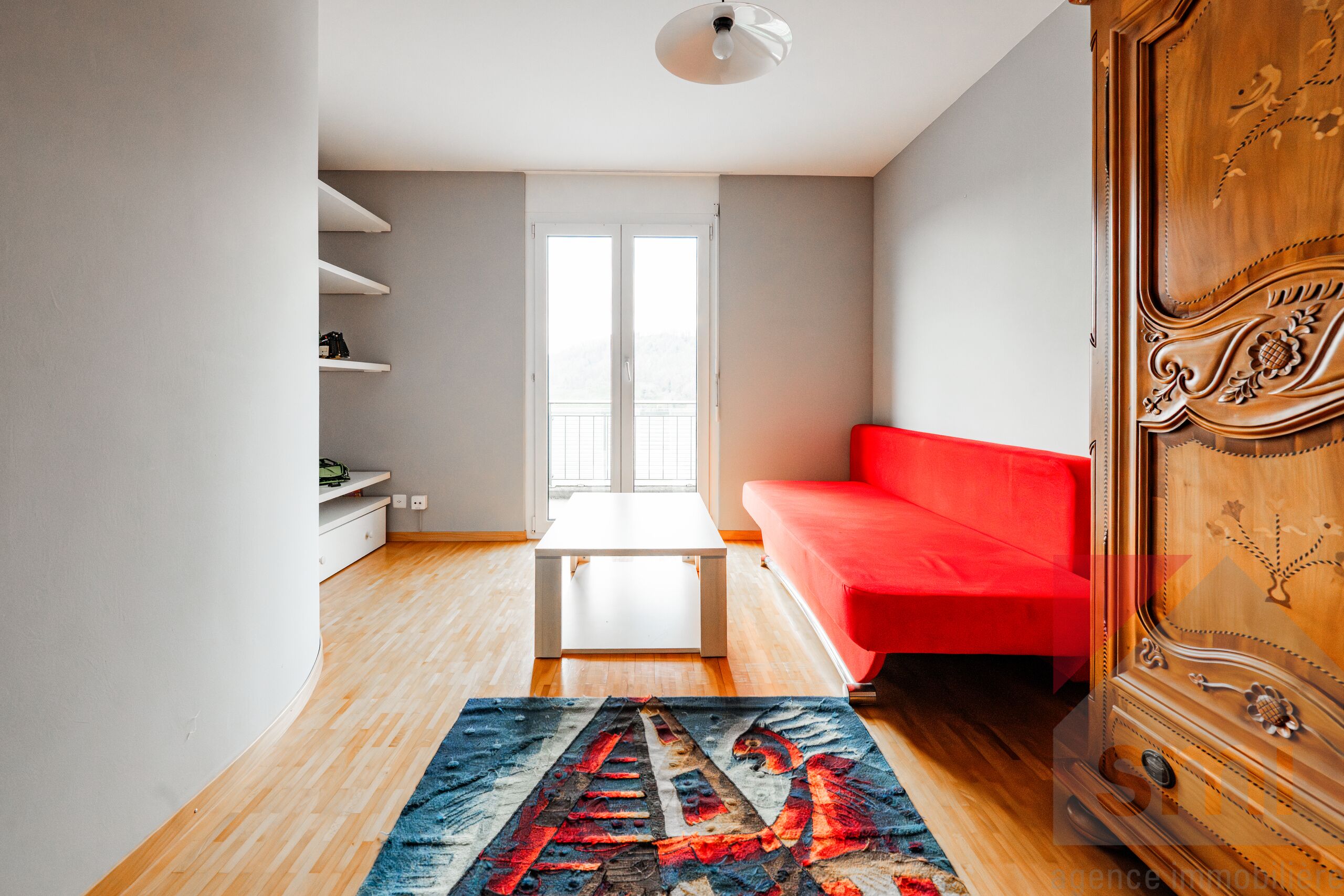 Helles Wohnzimmer mit rotem Sofa und Balkonblick
