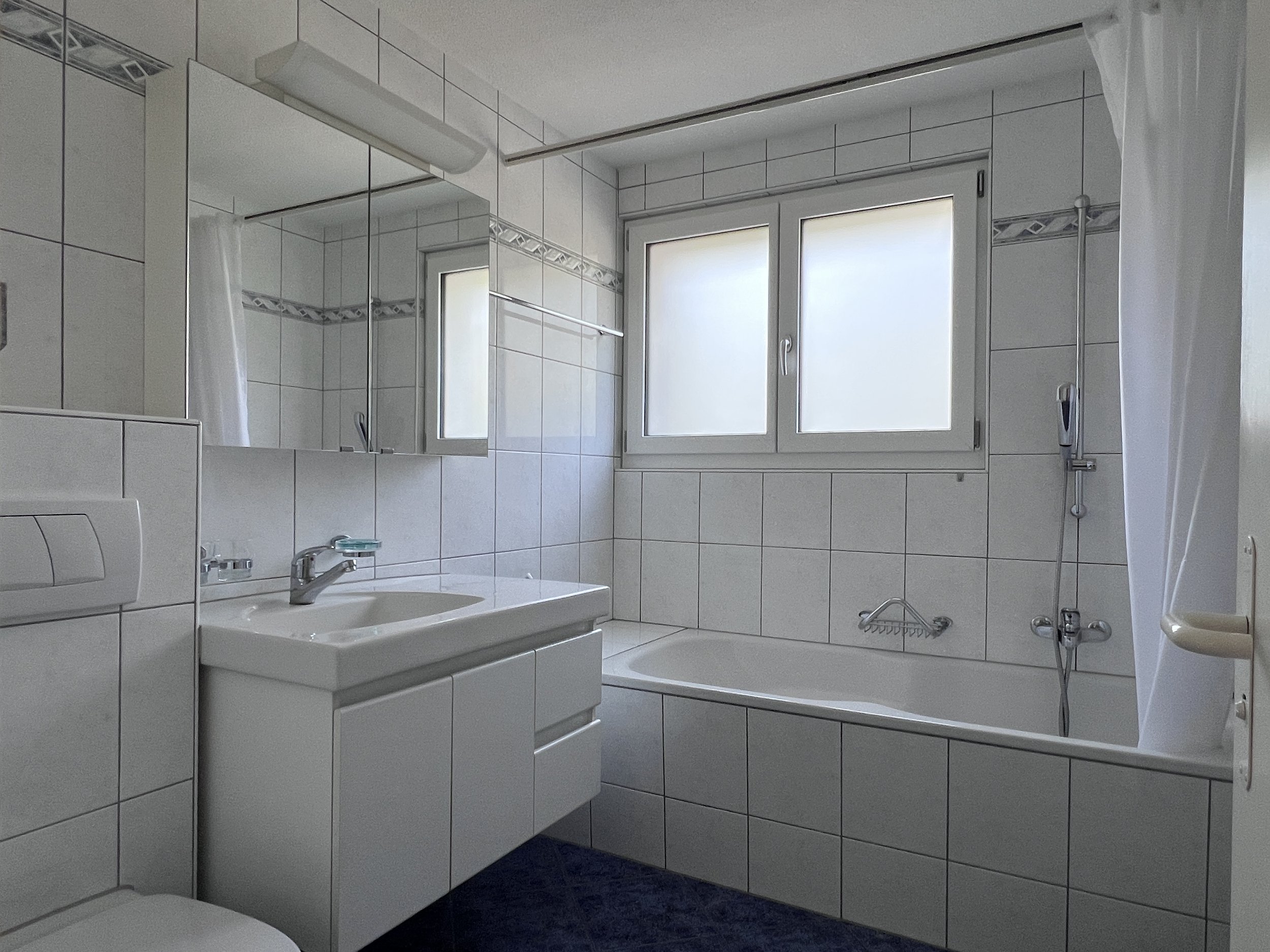 Helles Badezimmer mit Badewanne und Waschplatz
