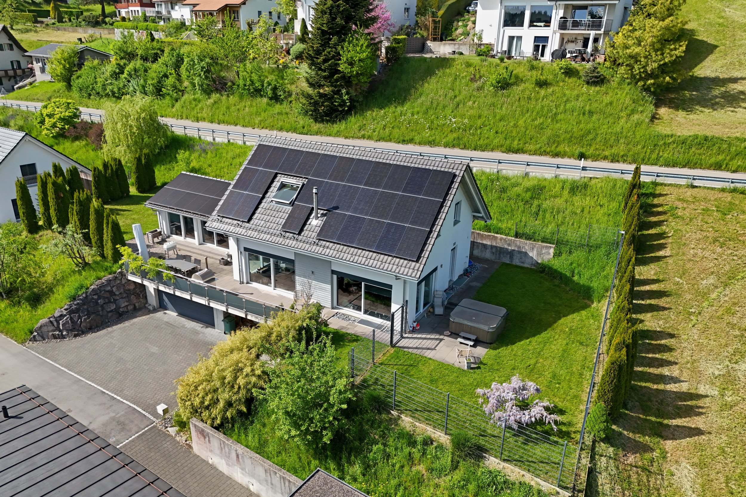 Luftaufnahme eines modernen Einfamilienhauses mit Solardach und großem Garten