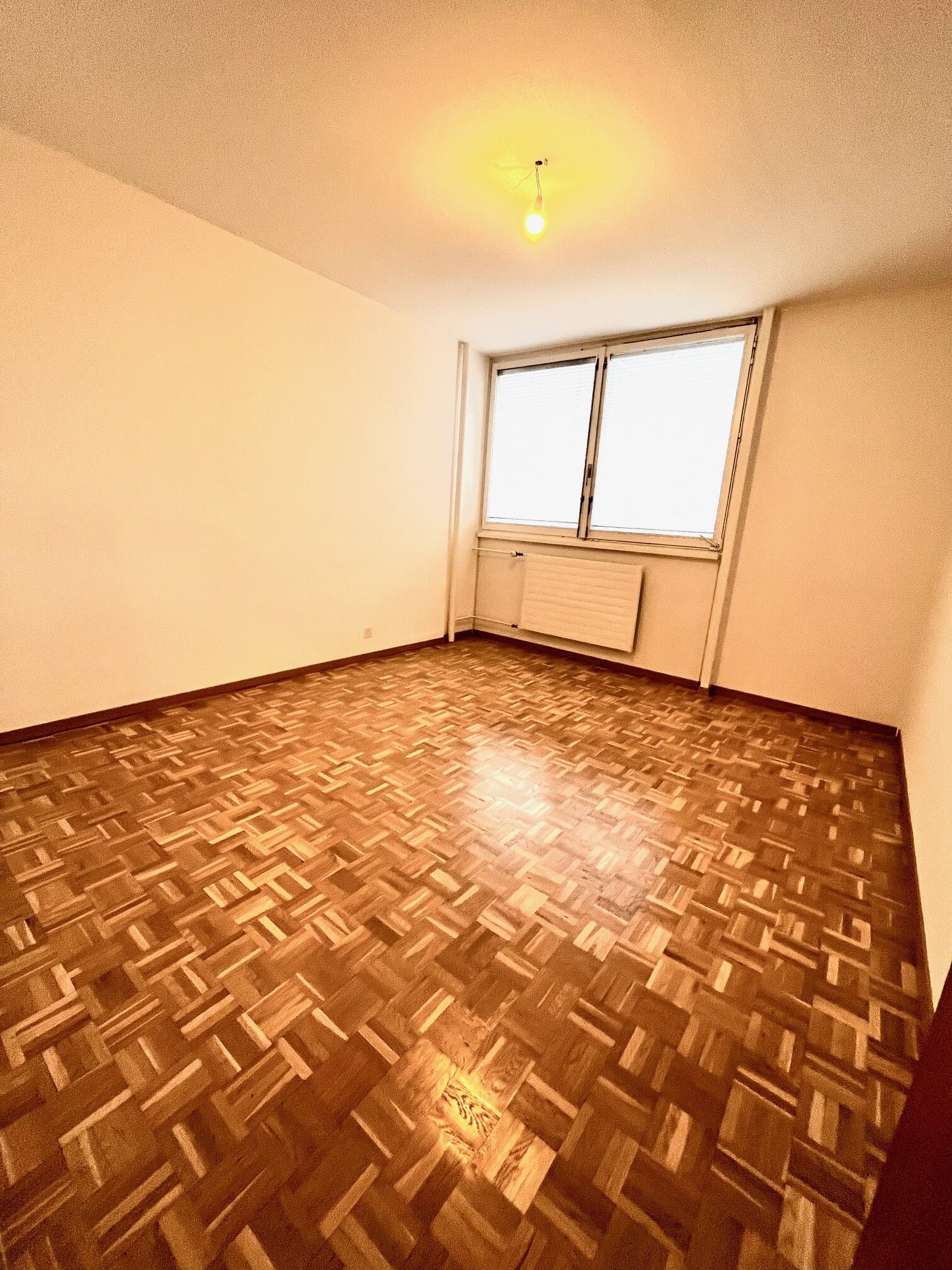 Leerer Wohnraum mit Parkett und Fenster