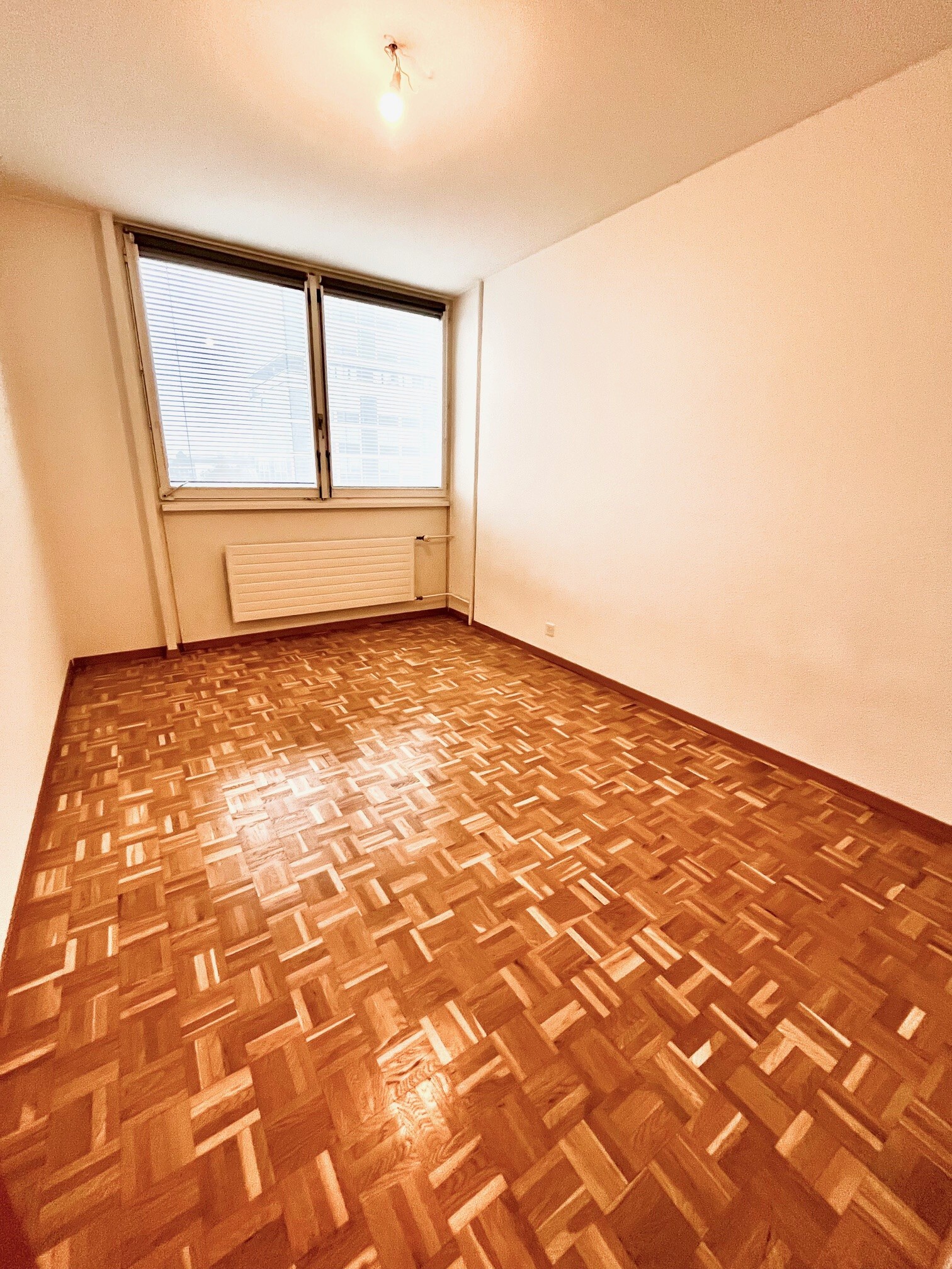 Leerer Wohnraum mit Parkett und Fenster