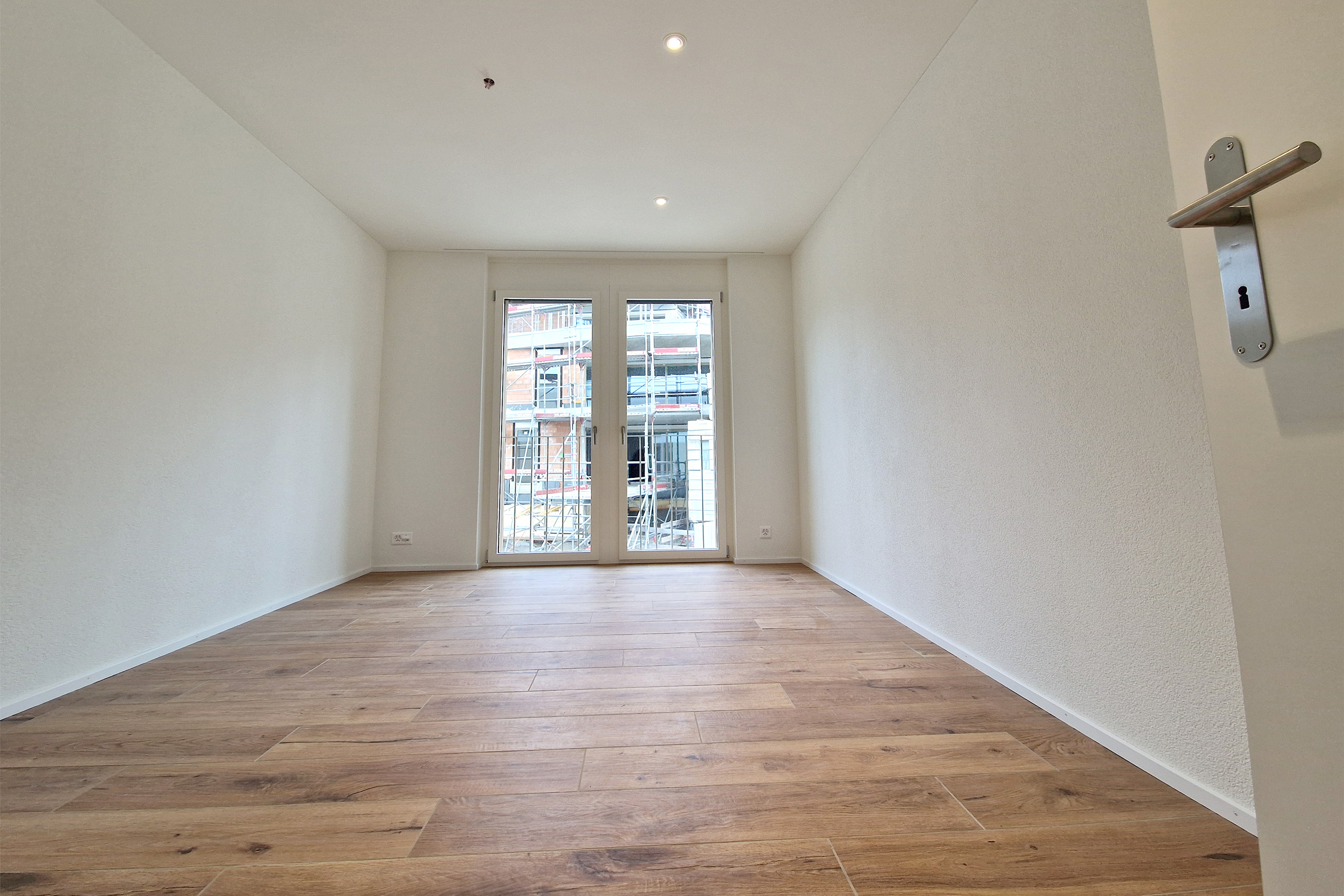 Leerer, frisch renovierter Raum mit Balkon- oder Fenstertür