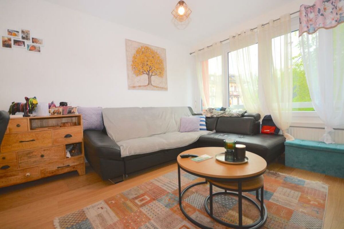 Gemütliches Wohnzimmer mit Ecksofa und großen Fenstern