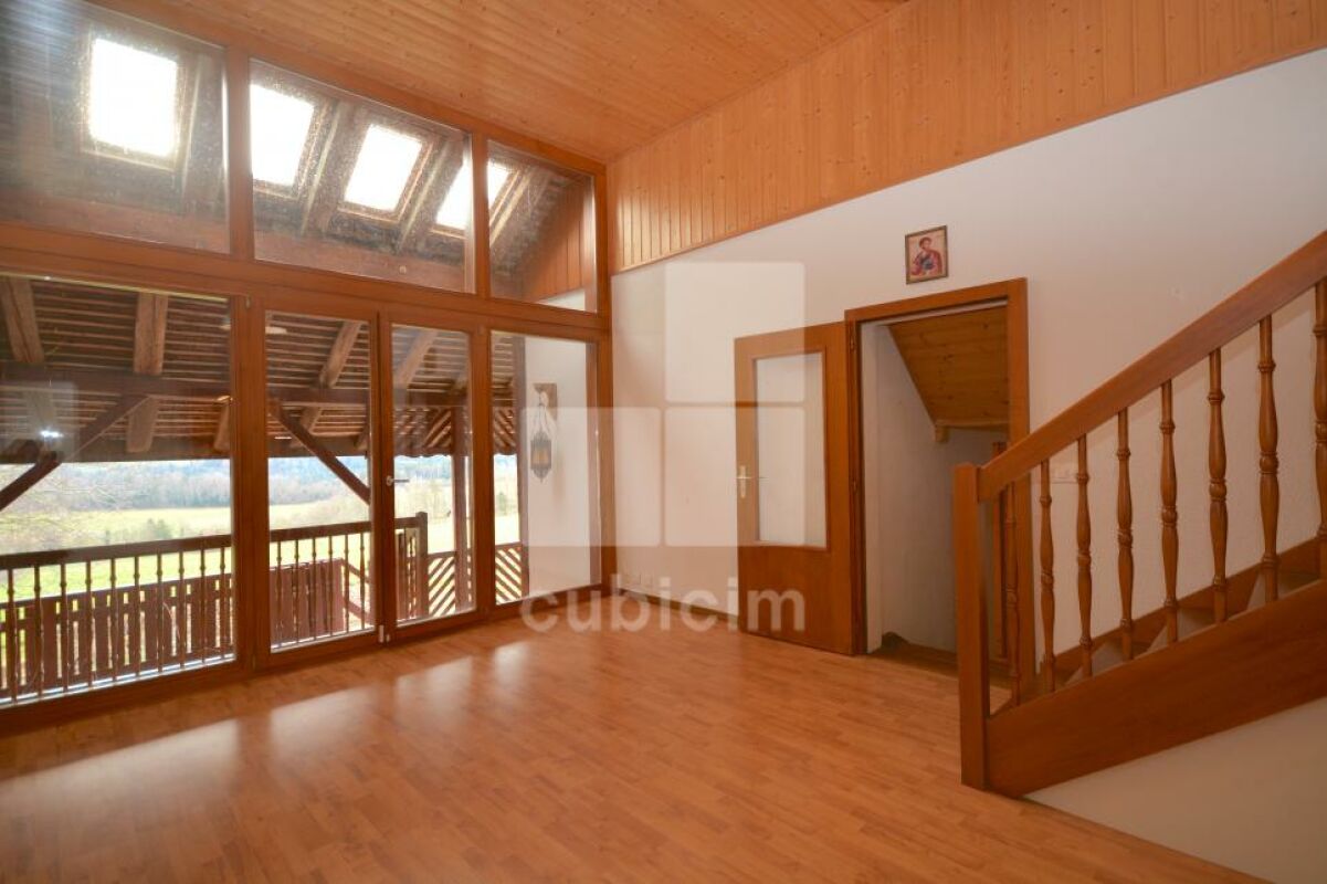 Heller Wohnraum mit großer Fensterfront und Holztreppe