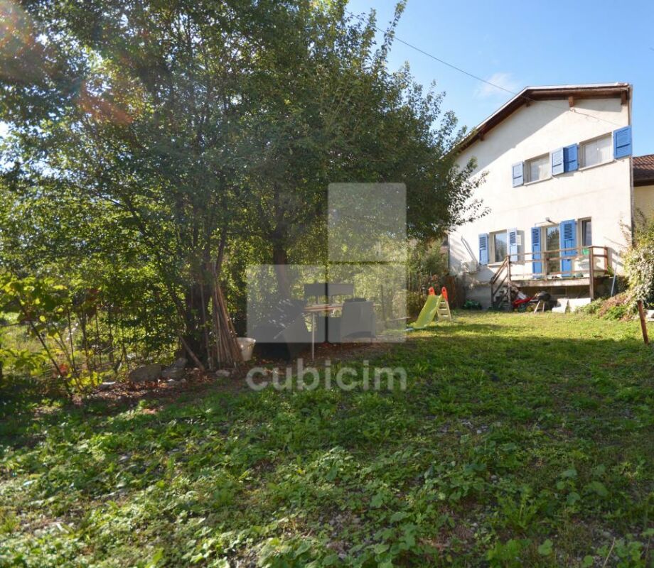 Gartenansicht eines Hauses mit Balkon und blau lackierten Fensterläden