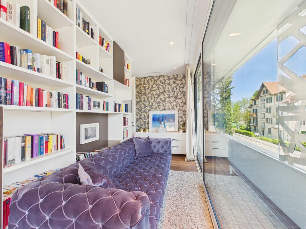 Heller Wohnraum mit Bibliothekswand und Balkonblick