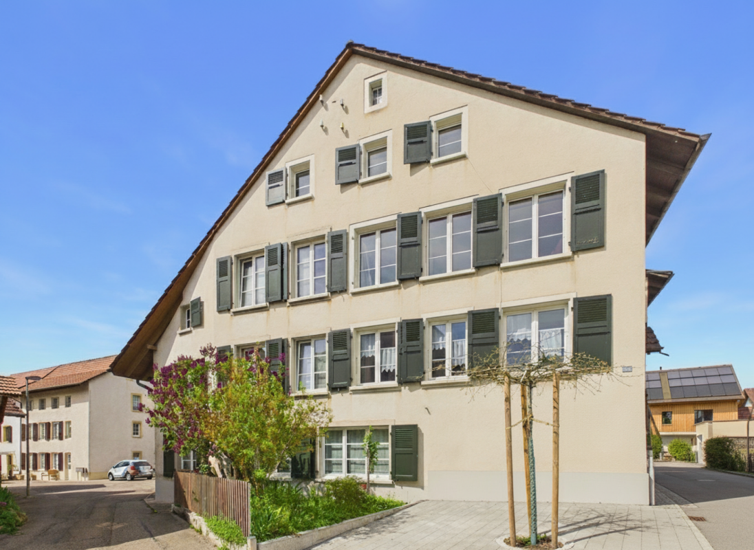 Mehrfamilienhaus mit Satteldach und grünen Fensterläden