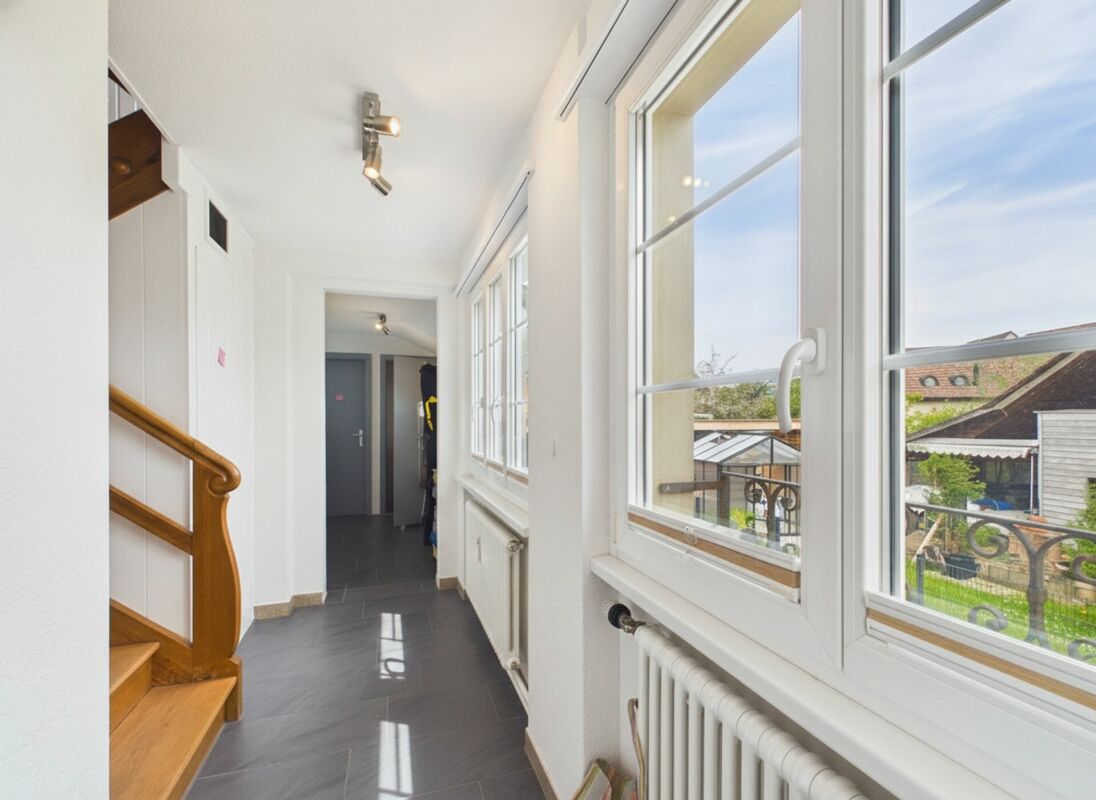 Heller Flur mit Treppe und großen Fenstern