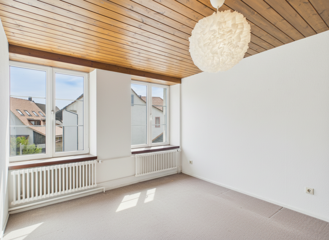 Heller leerer Raum mit Holzdecke und zwei Fenstern