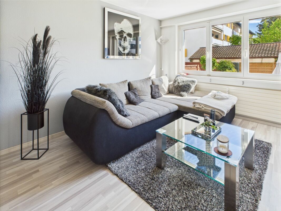 Helles Wohnzimmer mit Ecksofa und großem Fenster