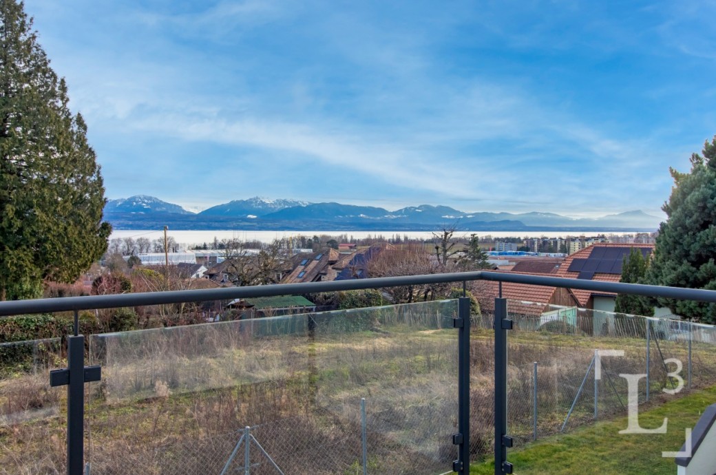 Blick von einer Terrasse mit Geländer auf See und Berge