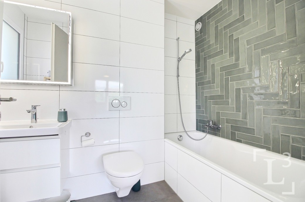 Modernes Badezimmer mit weißer Sanitärkeramik und grünem Fliesendetail