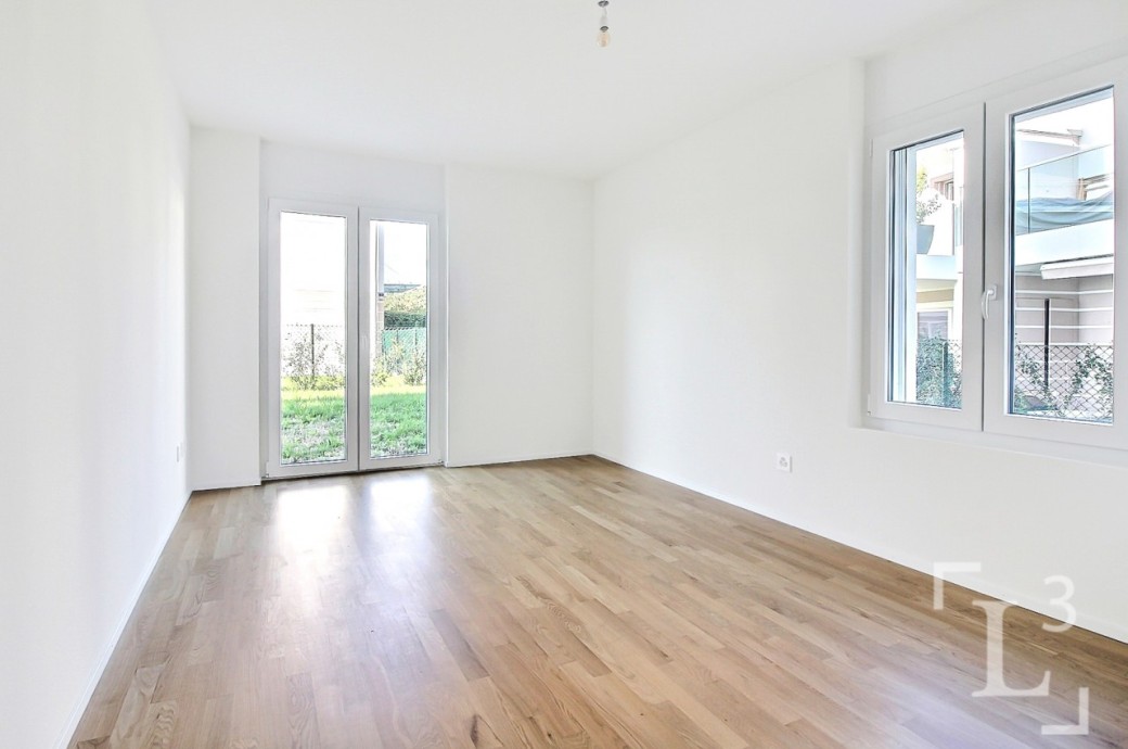 Heller leerer Wohnraum mit Holzfußboden und Fenstern zum Außenbereich