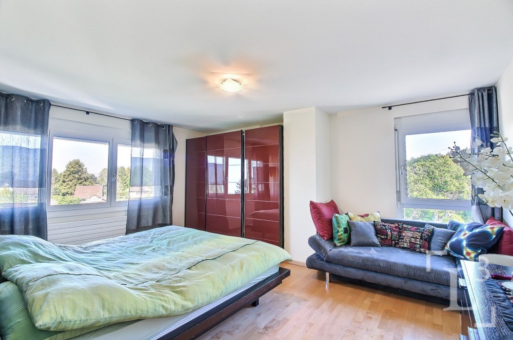 Helles Schlafzimmer mit Sofa und großen Fenstern
