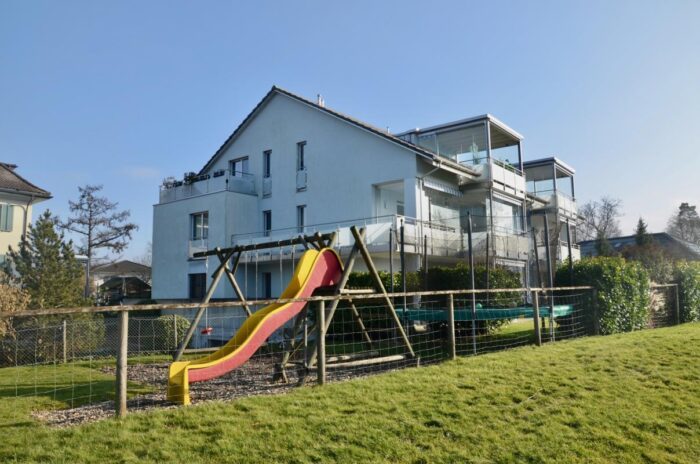 Außenansicht eines modernen Wohnhauses mit Garten und Spielbereich