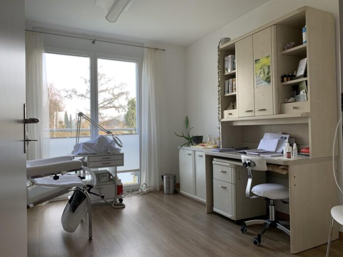 Behandlungszimmer mit Schreibtisch und Liege
