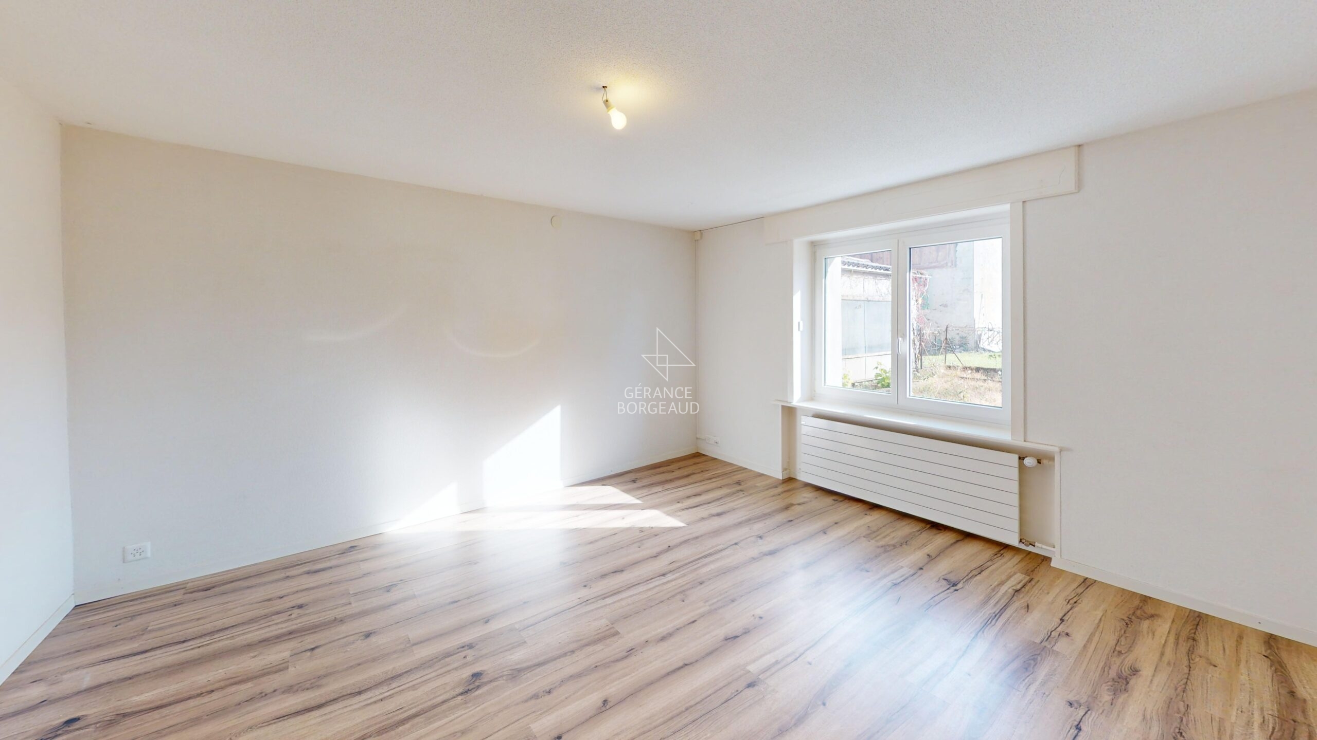 Heller leerer Raum mit Fenster und Holzoptikboden