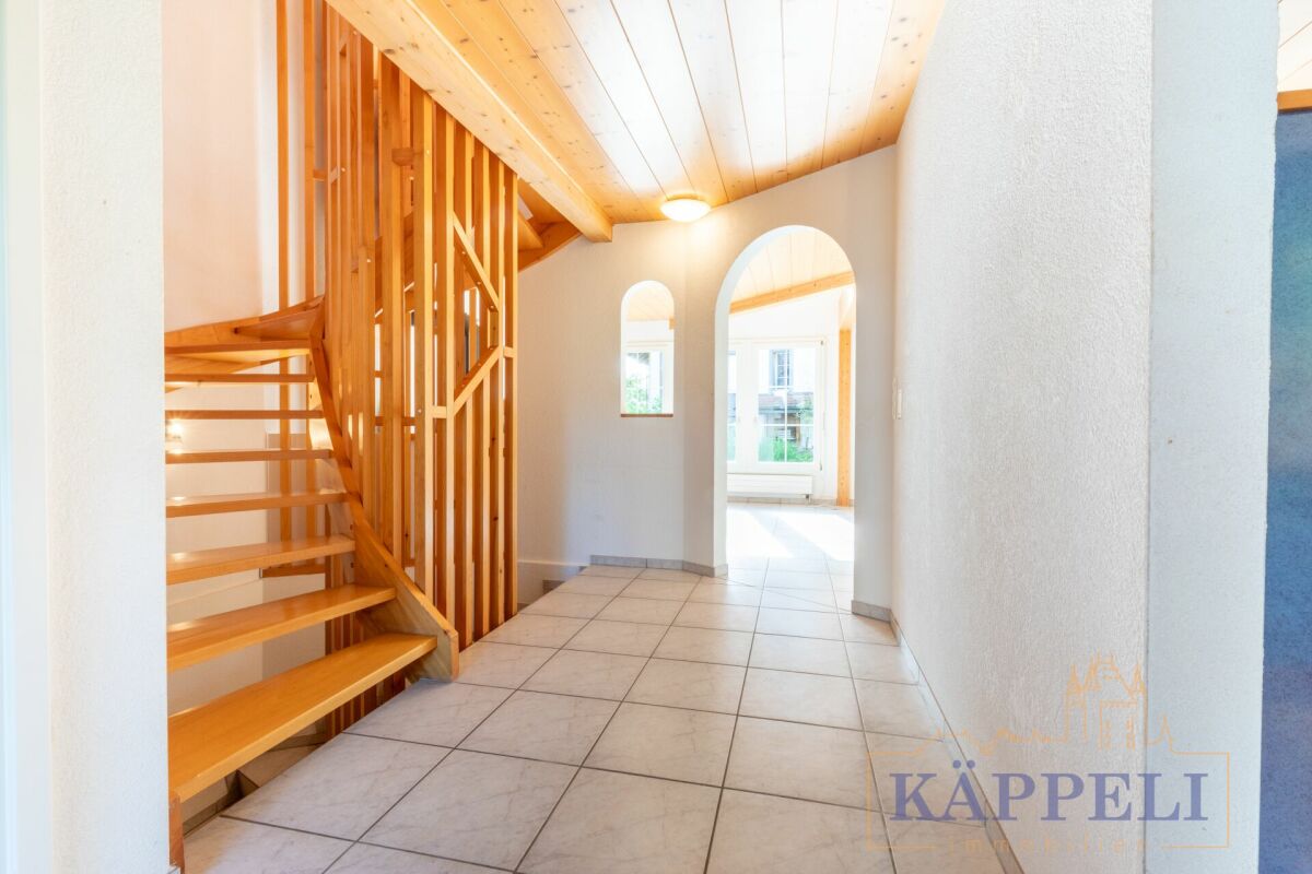 Heller Eingangsflur mit Holztreppe